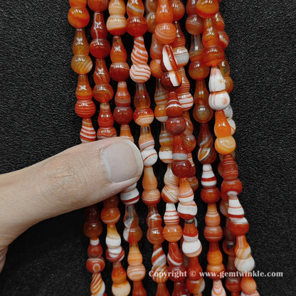 Close up view of color-dyed banded agate calabash beads held on fingers for quality preview