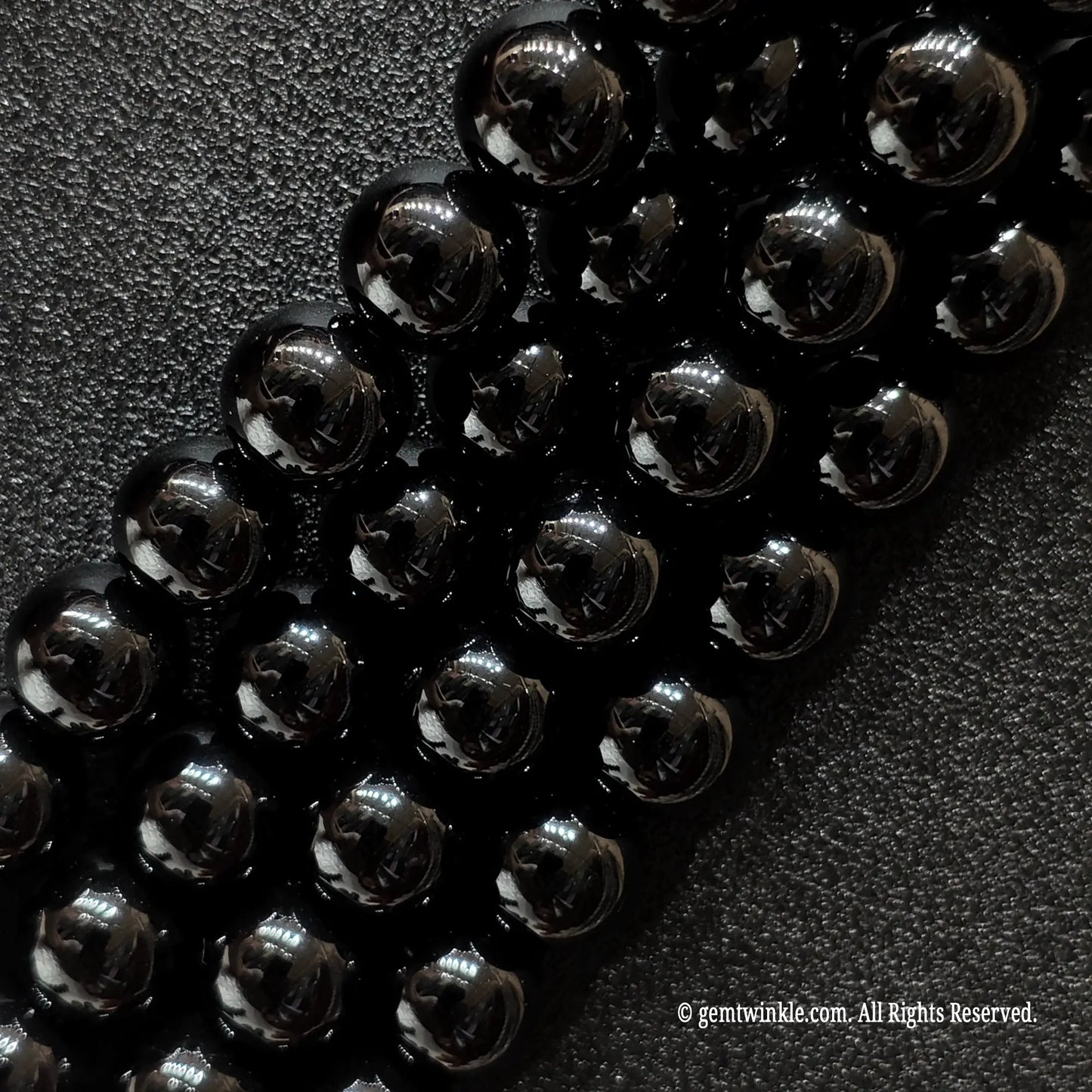 Angled view of smooth black agate jewelry beads showing uniform polish