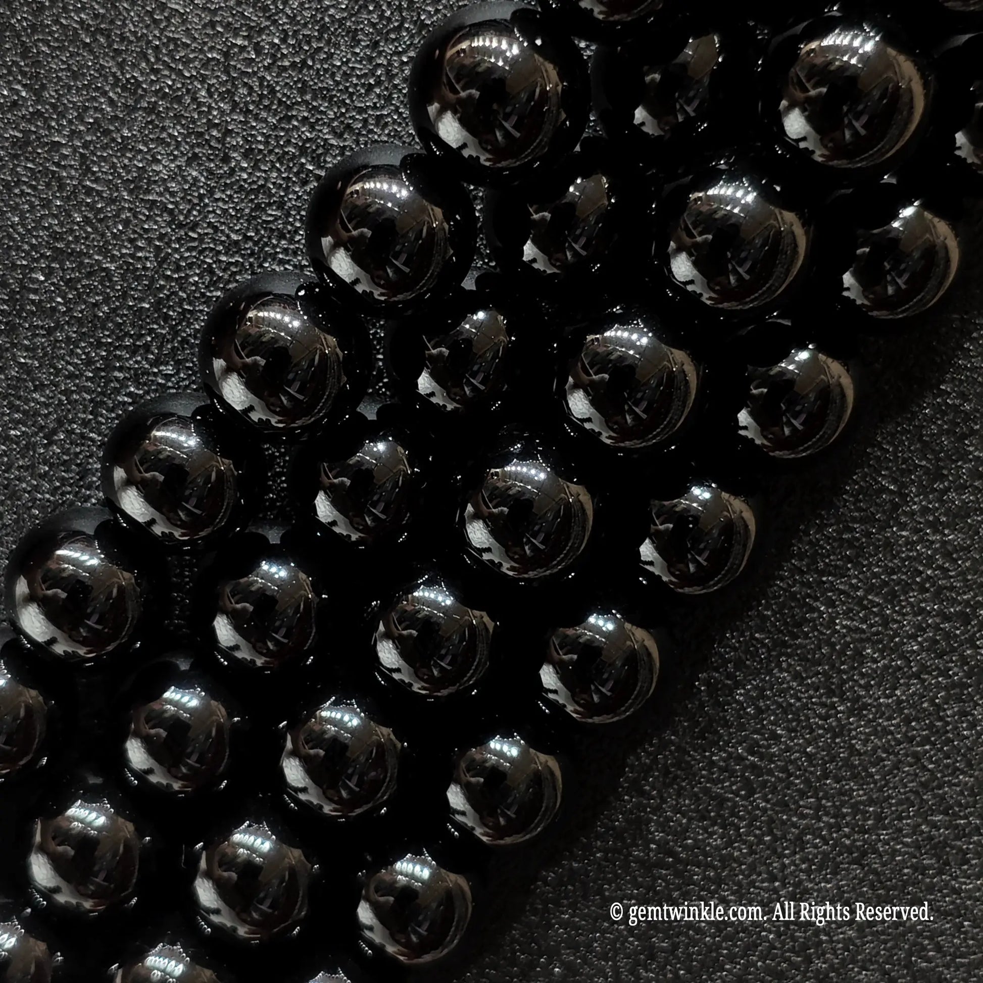 Angled view of smooth black agate jewelry beads showing uniform polish