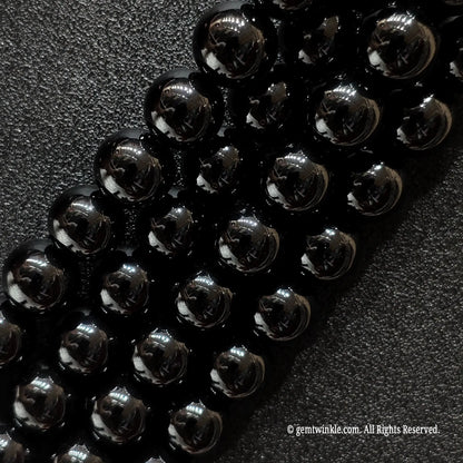 Angled view of smooth black agate jewelry beads showing uniform polish
