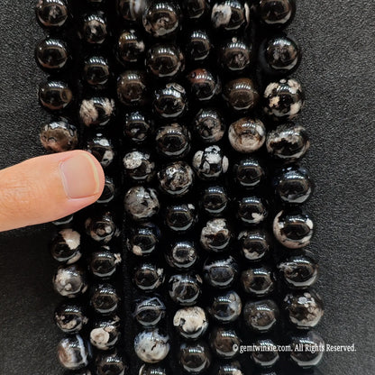 Inspecting a batch of dyed black chalcedony crystal beads from 6mm to 16mm with natural agate base for store size chart validation