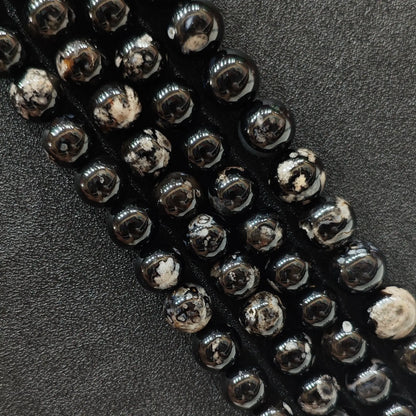 Close up view of dyed black cherry blossom agate crystal beads strands showing high contrast white floral plumes over a natural agate base in image_be1c2a.jpg