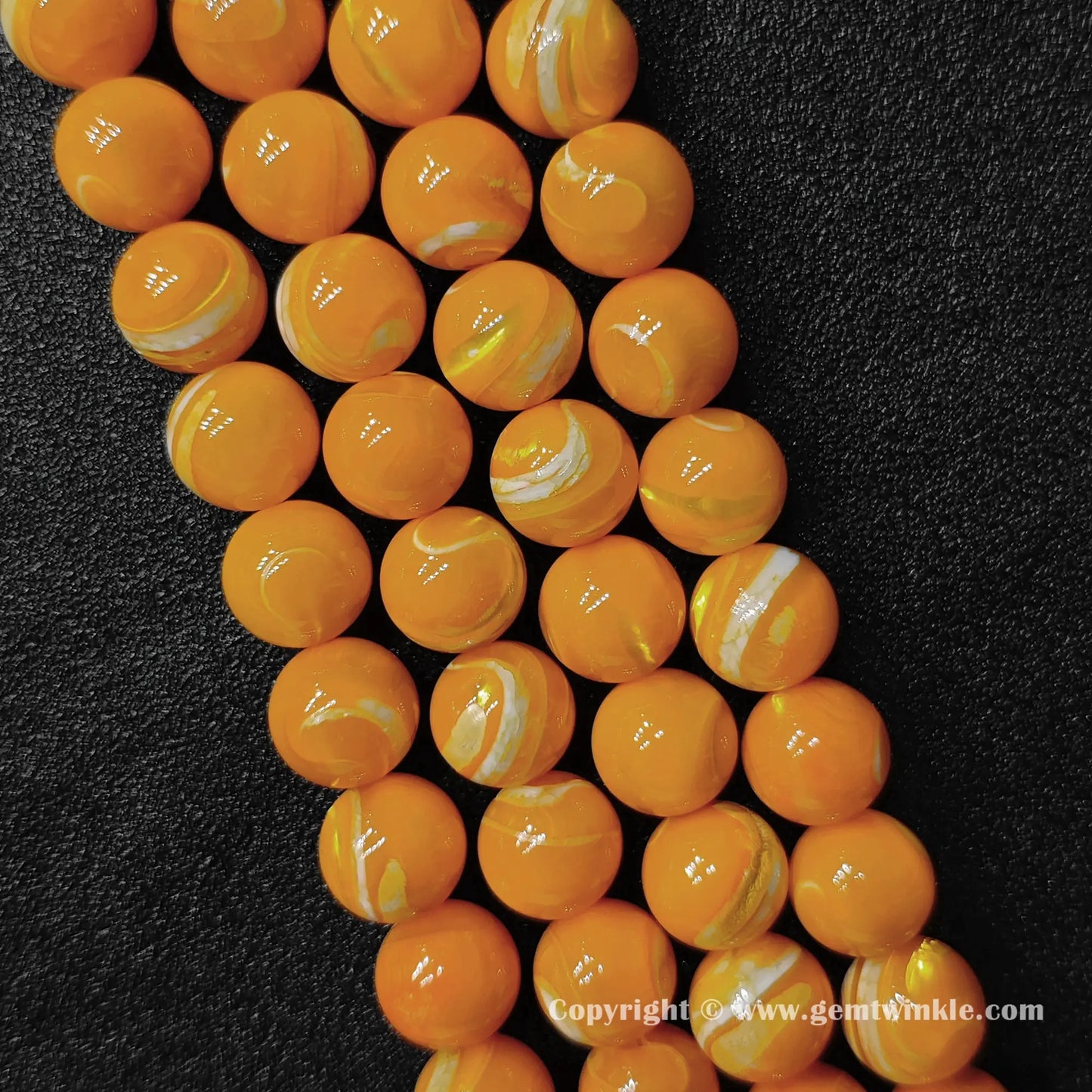 Close up view of dyed yellow mother of pearl beads showing glossy surface and swirl layers