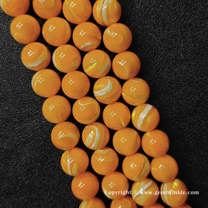 Close up view of dyed yellow mother of pearl beads showing glossy surface and swirl layers