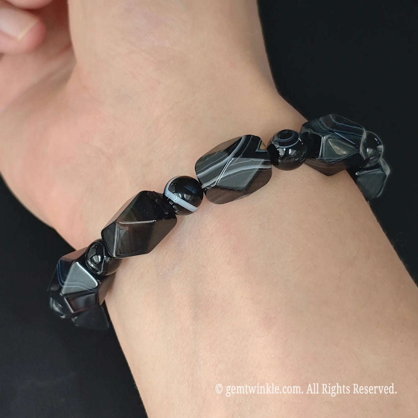 Dyed black banded agate faceted geometric nugget stretch bracelet styled on wrist displaying high contrast silk layers