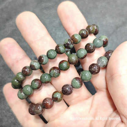Close up view of natural phantom crystal beads highlighting rustic red and green mineral inclusions