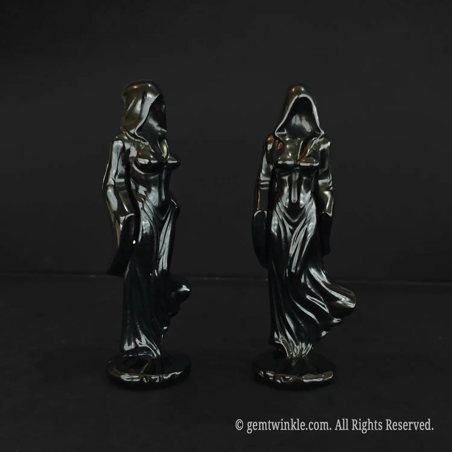 Front and back views of the faceless cloaked witch statue carved from glossy black obsidian showcasing the draped hood