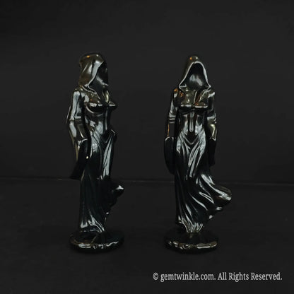 Front and back views of the faceless cloaked witch statue carved from glossy black obsidian showcasing the draped hood