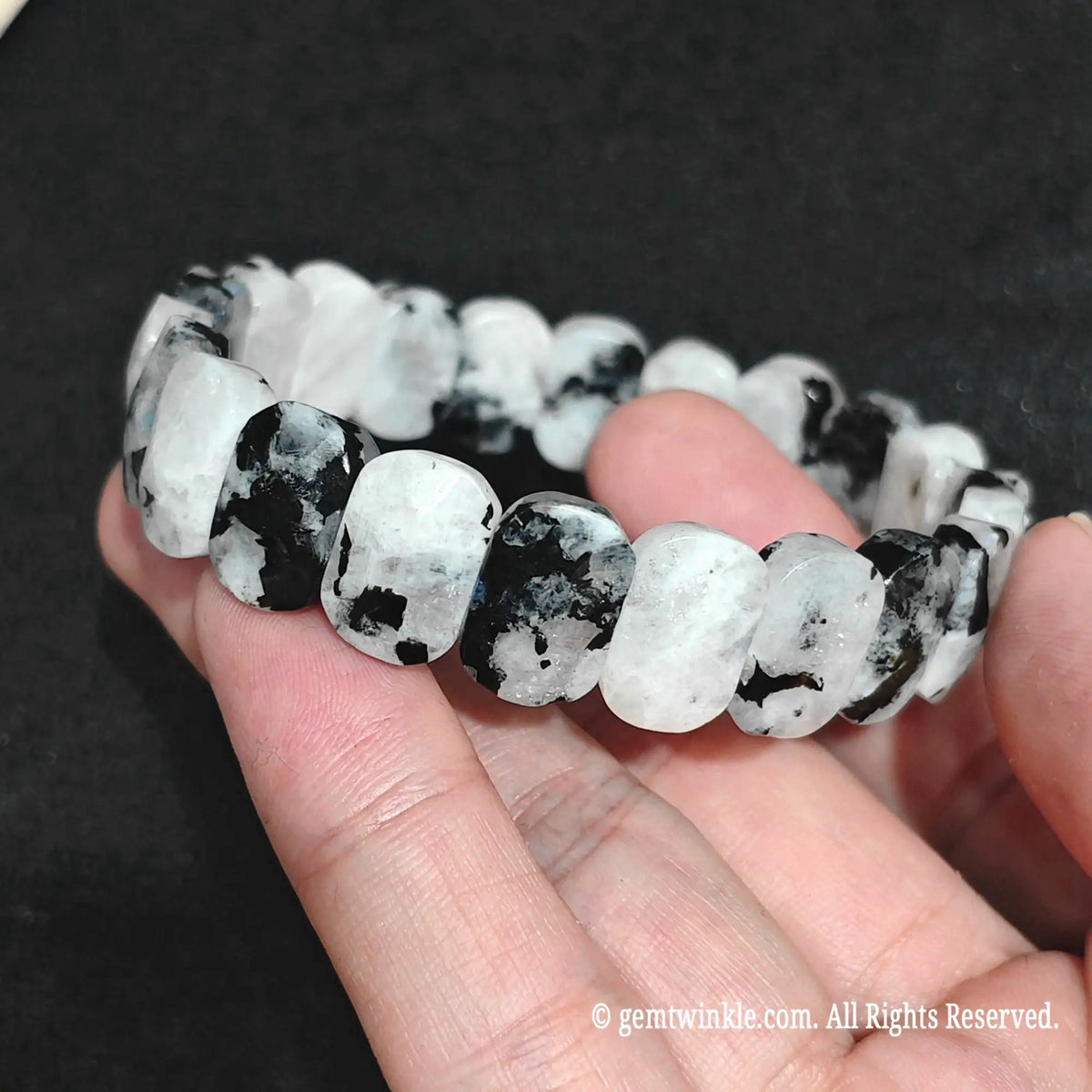 Hand holding a natural faceted black spot blue moonstone statement bracelet for wholesale buyers