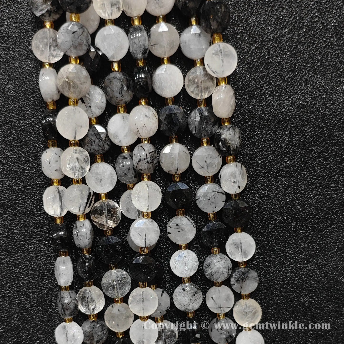 Vertical alignment of faceted black rutilated quartz coin beads on dark background