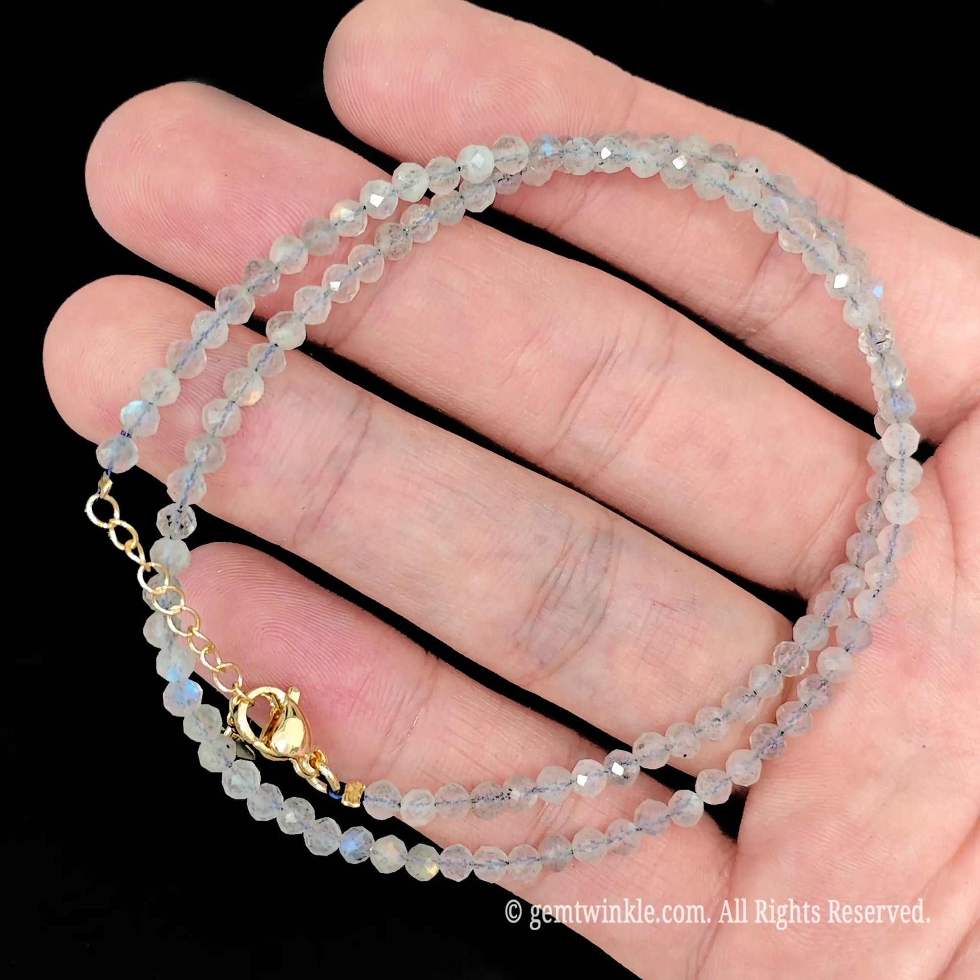 single strand grey moonstone beaded necklace coiled across palm showing translucent smoky grey tones