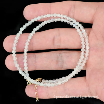single strand white moonstone beaded necklace coiled across palm showing subtle blue sheen