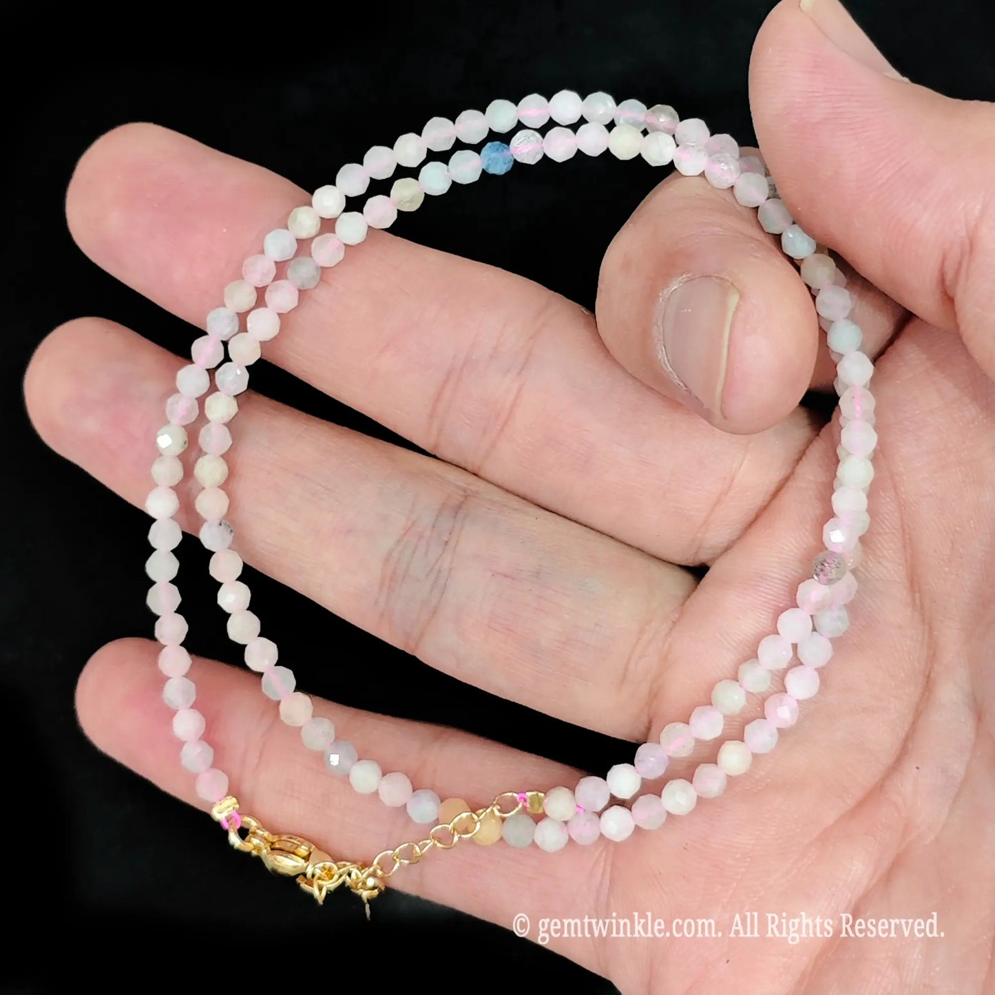 single strand morganite beaded necklace coiled across palm showing blush pink pastel tones