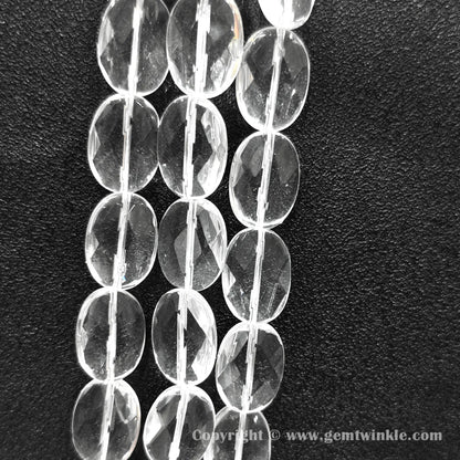 Vertical alignment of faceted oval slice clear quartz beads on dark background