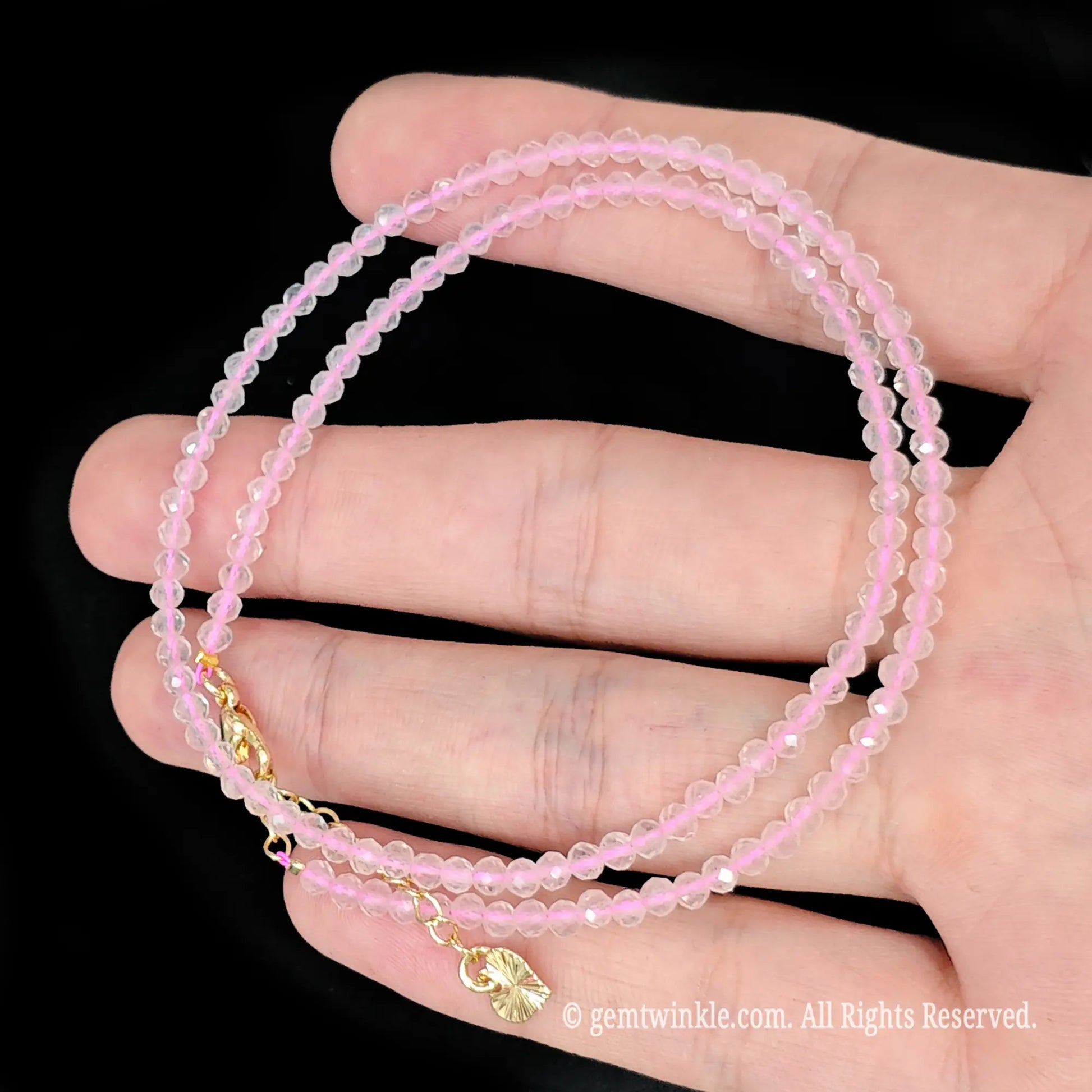single strand rose quartz beaded necklace coiled across palm showing translucent soft pink color