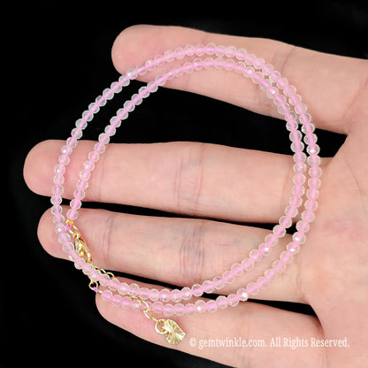 single strand rose quartz beaded necklace coiled across palm showing translucent soft pink color