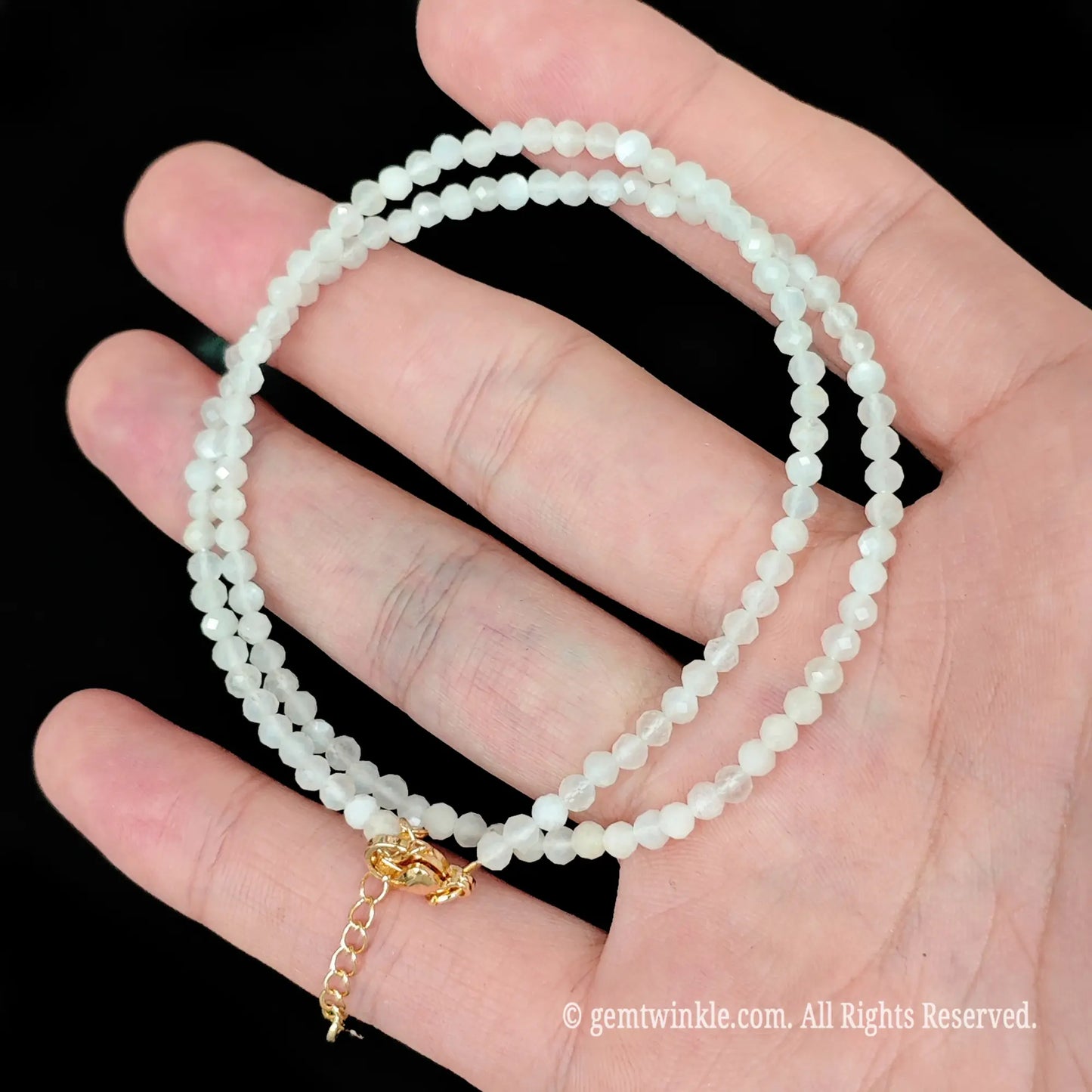 single strand white moonstone beaded necklace coiled over palm showing soft milky glow
