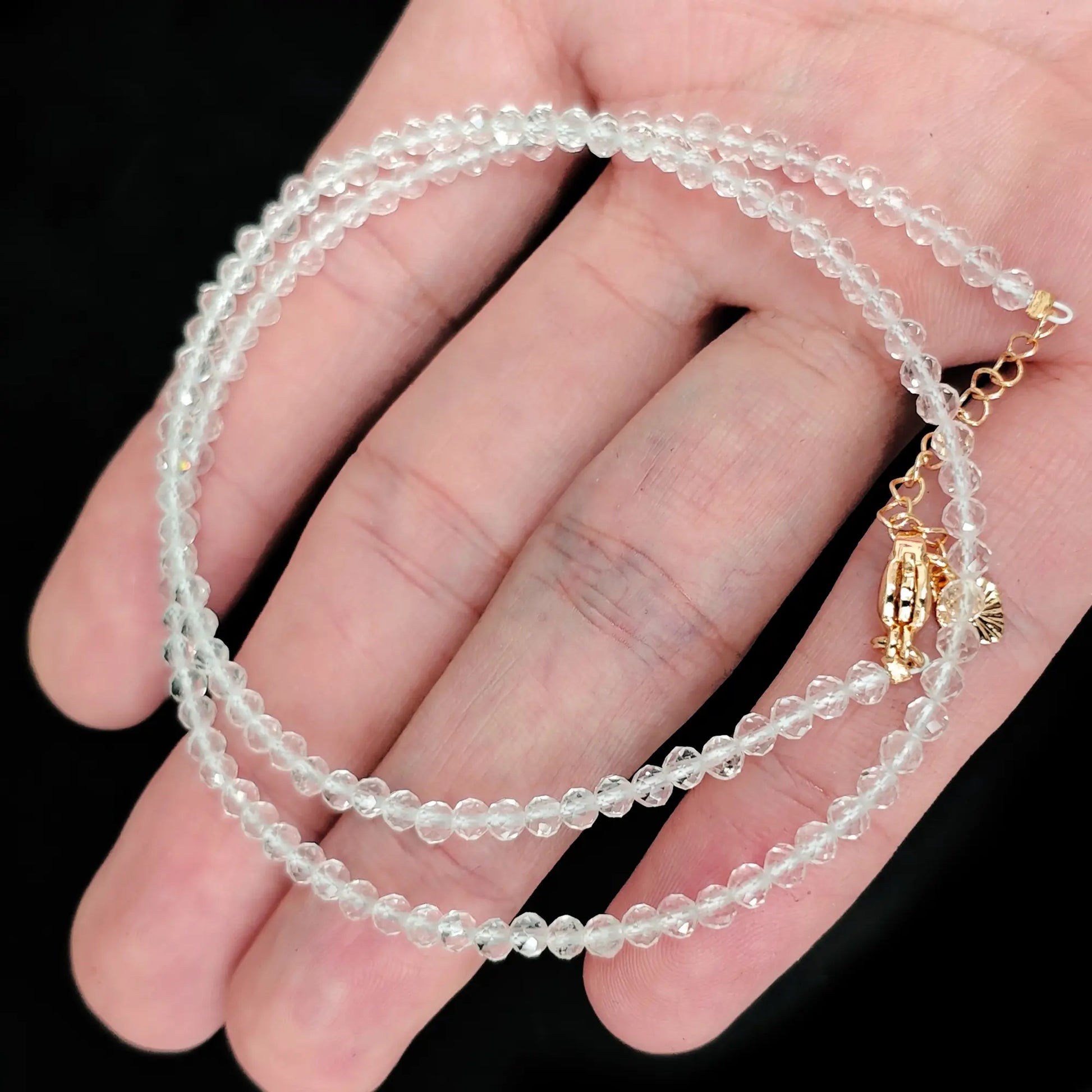 single strand clear quartz beaded necklace coiled across palm showing transparent icy clarity