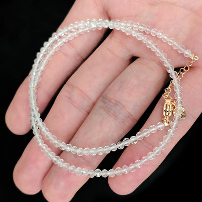 single strand clear quartz beaded necklace coiled across palm showing transparent icy clarity