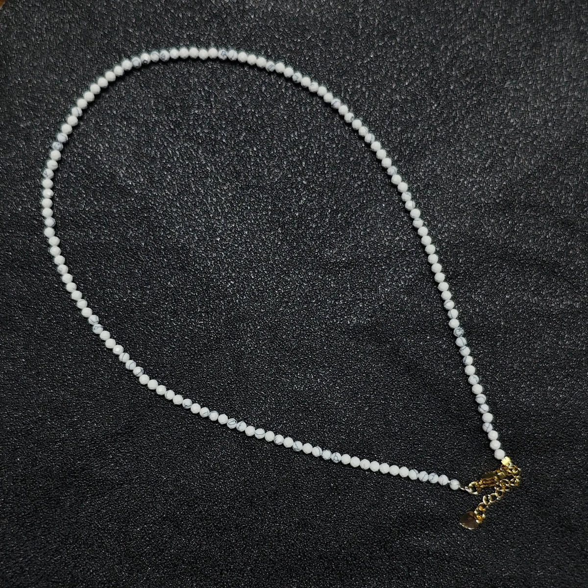 Natural faceted white howlite turquoise necklace with 3mm beads and gold extender chain layout