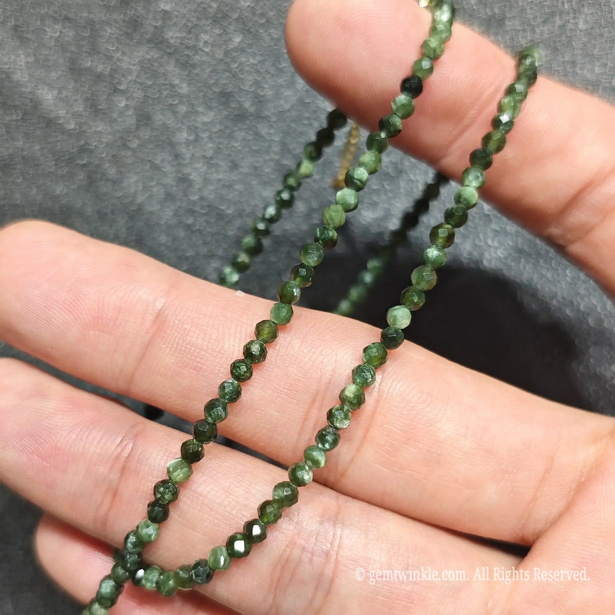 Coiled 3mm faceted green seraphinite necklace demonstrating silvery chatoyant luster across beads