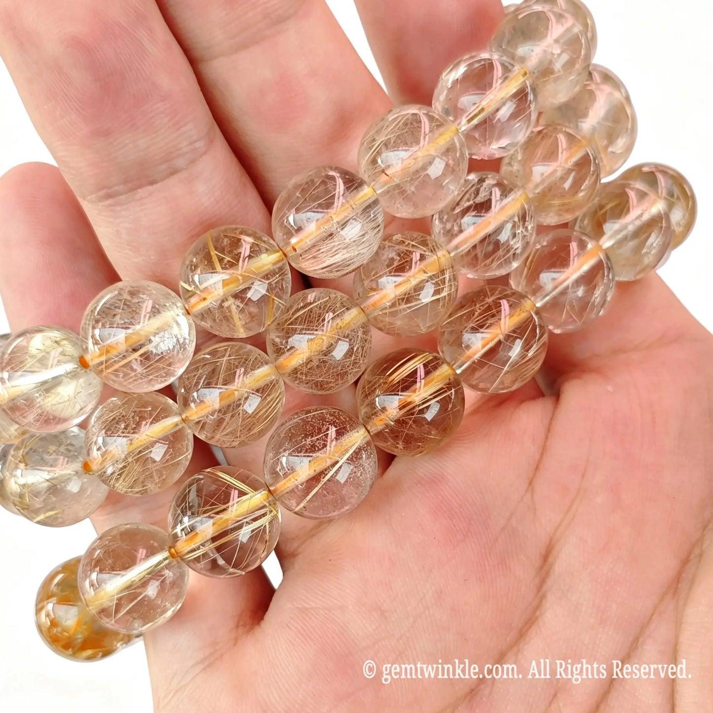 Close up preview of fine hair gold rutilated quartz round beads highlighting smooth polish