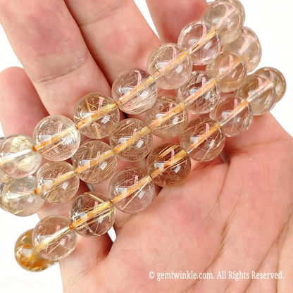 Close up preview of fine hair gold rutilated quartz round beads highlighting smooth polish