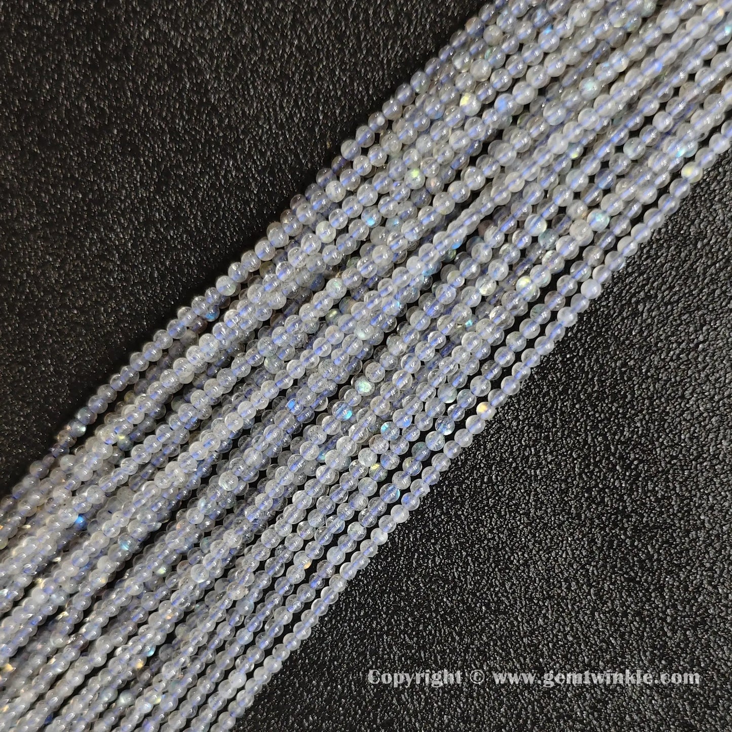 Flatlay alignment of fine grey blue moonstone micro gemstone strands highlighting petite bead uniform drilling