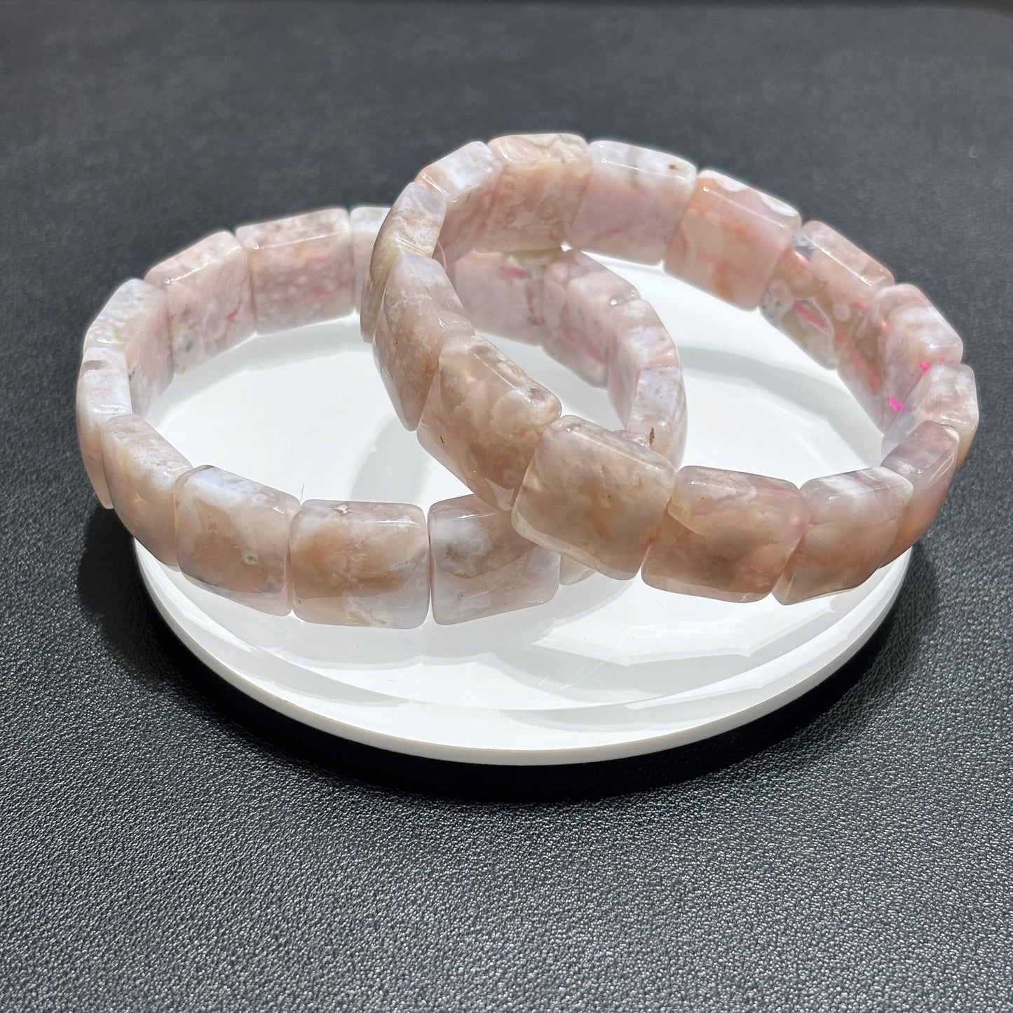 Close up of natural flower agate bangle with pink and white crystal patterns.
