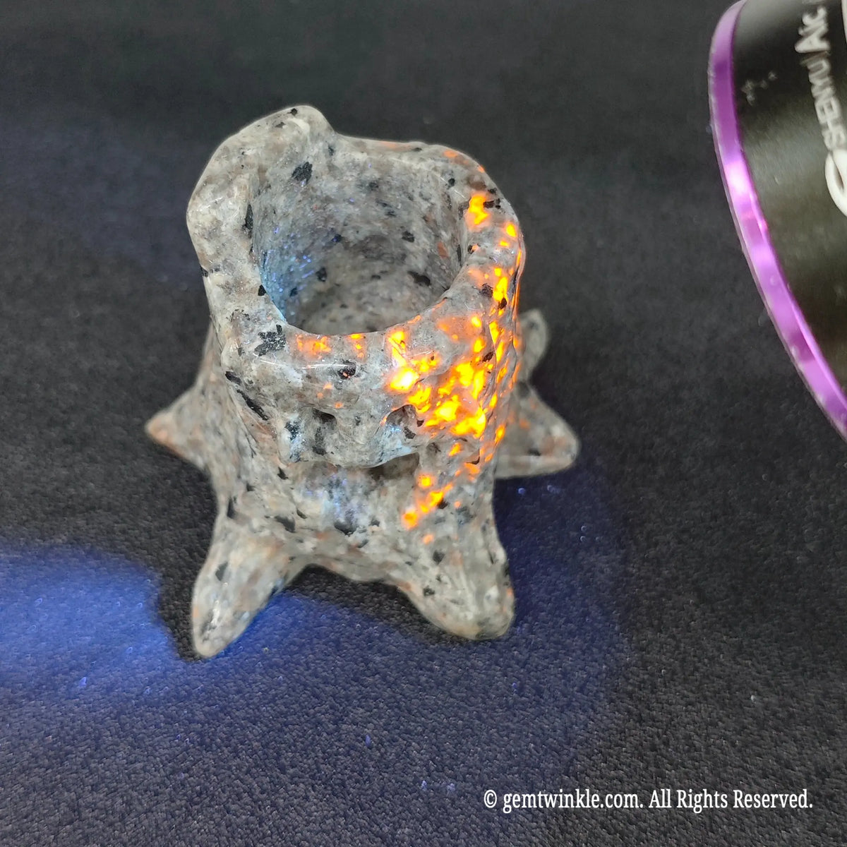 Carved yooperlite tree stump glowing with orange lava sodalite spots under 365nm UV blacklight