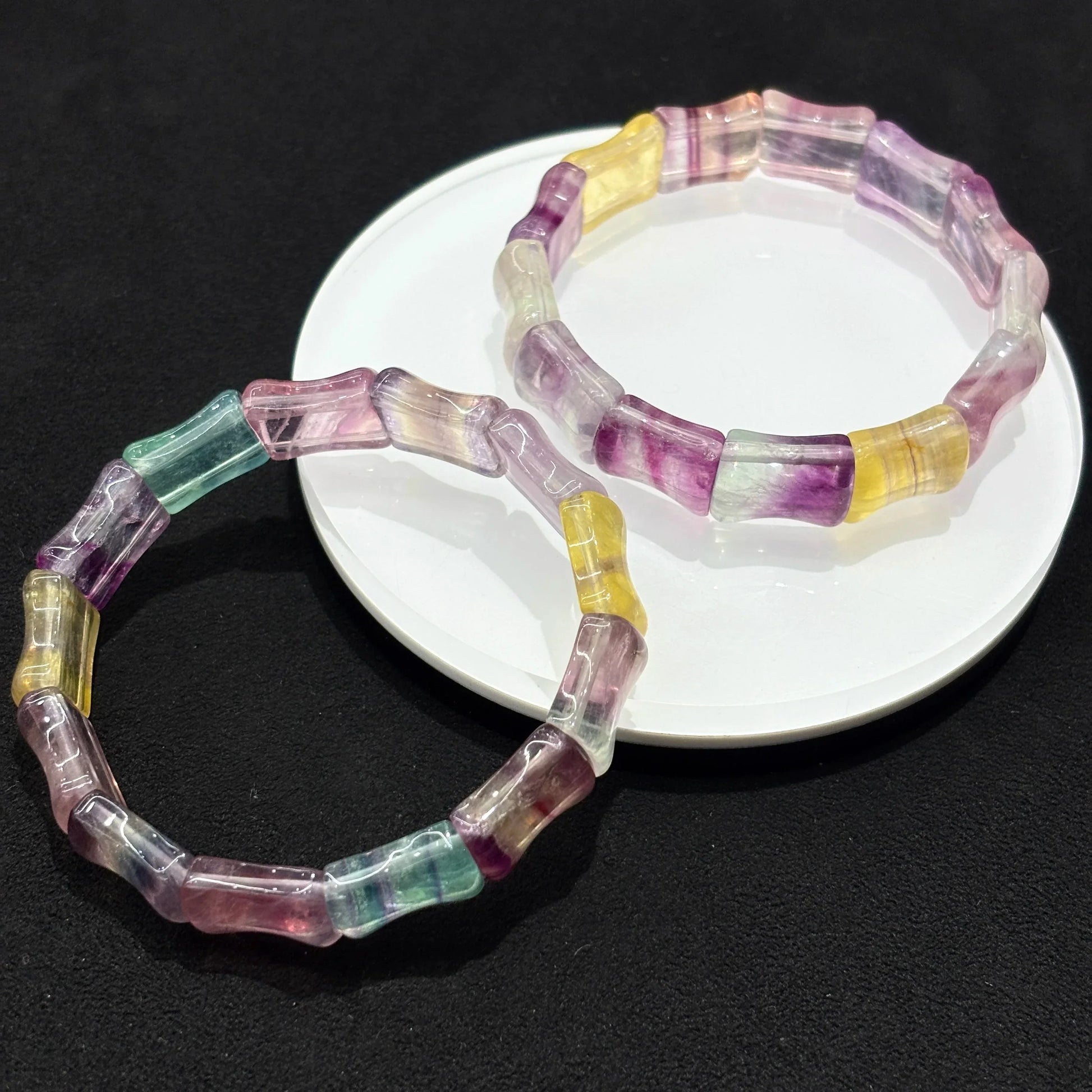 Two Natural Colorful Fluorite Bamboo Bead Bangle Bracelets stacked together on white plate, black background, showcasing matching set
