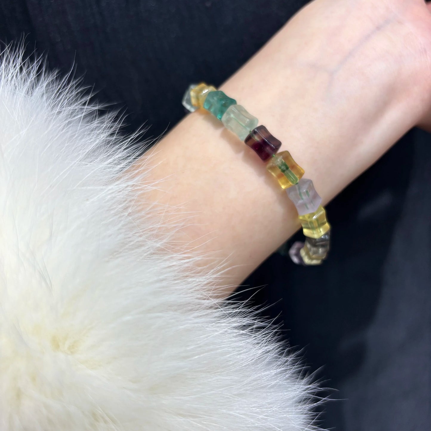 A person wearing a colorful fluorite bamboo bangle on their wrist, showcasing how the natural stone bracelet fits comfortably for daily wear.