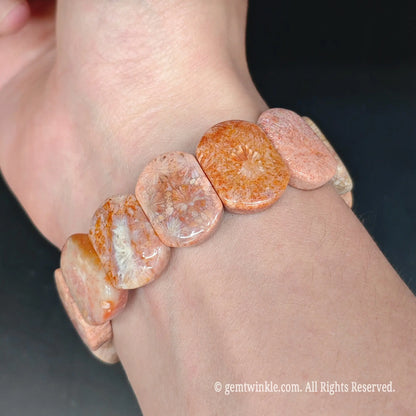 Fossilized coral jade smooth tile bead stretch bracelet styled on wrist displaying warm peach color and comfortable fit