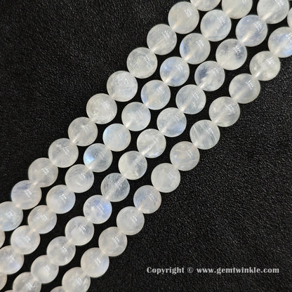 Angled view of blue flash moonstone round bead strands with ice fracture texture laid parallel on dark background