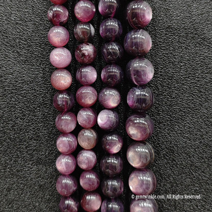 Purple lepidolite crystal beads strands displaying delicate lavender color shades under direct lighting