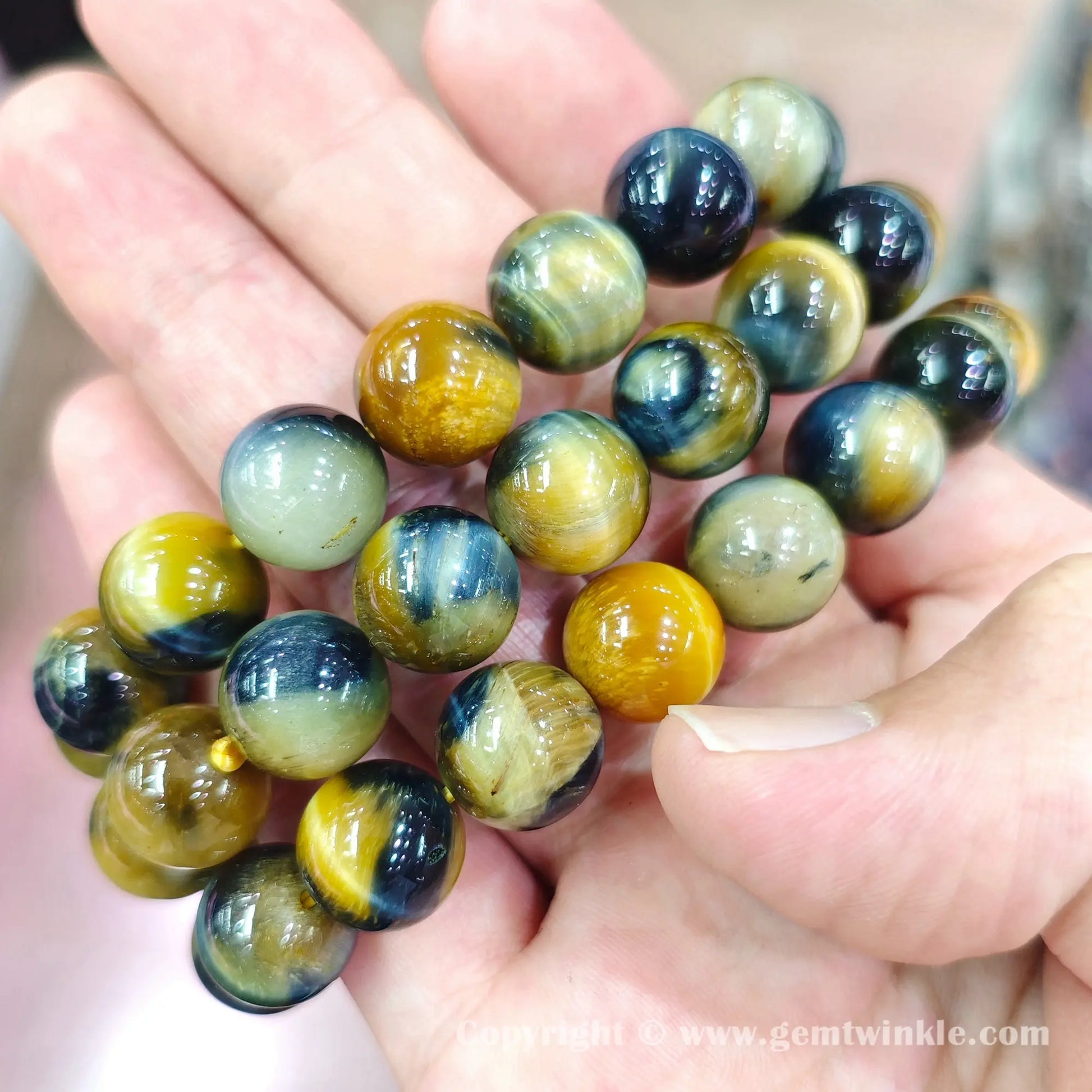 Handheld view showing blue yellow tiger eye bead polish and color contrast on elastic cord
