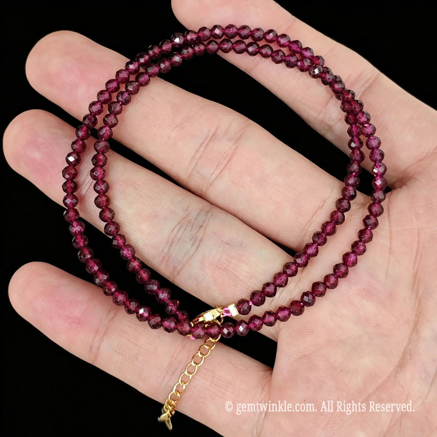 red garnet faceted micro bead necklace loop with gold tone extender chain in hand