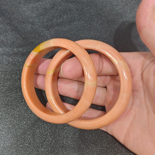 Gem's Twinkle Natural Apricot Quartz solid gemstone bangle bracelet held on hand in warm cinnamon orange tones