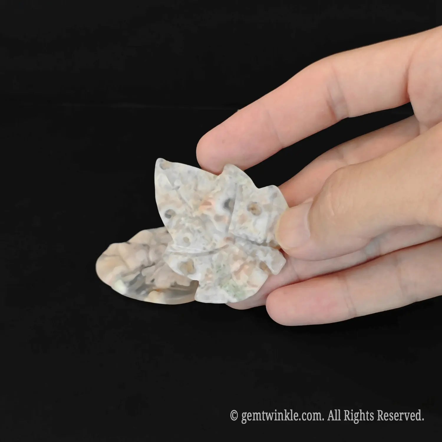 Handheld view of a cherry blossom agate leaf crystal carving showing detailed carved recessed veins and fine polish