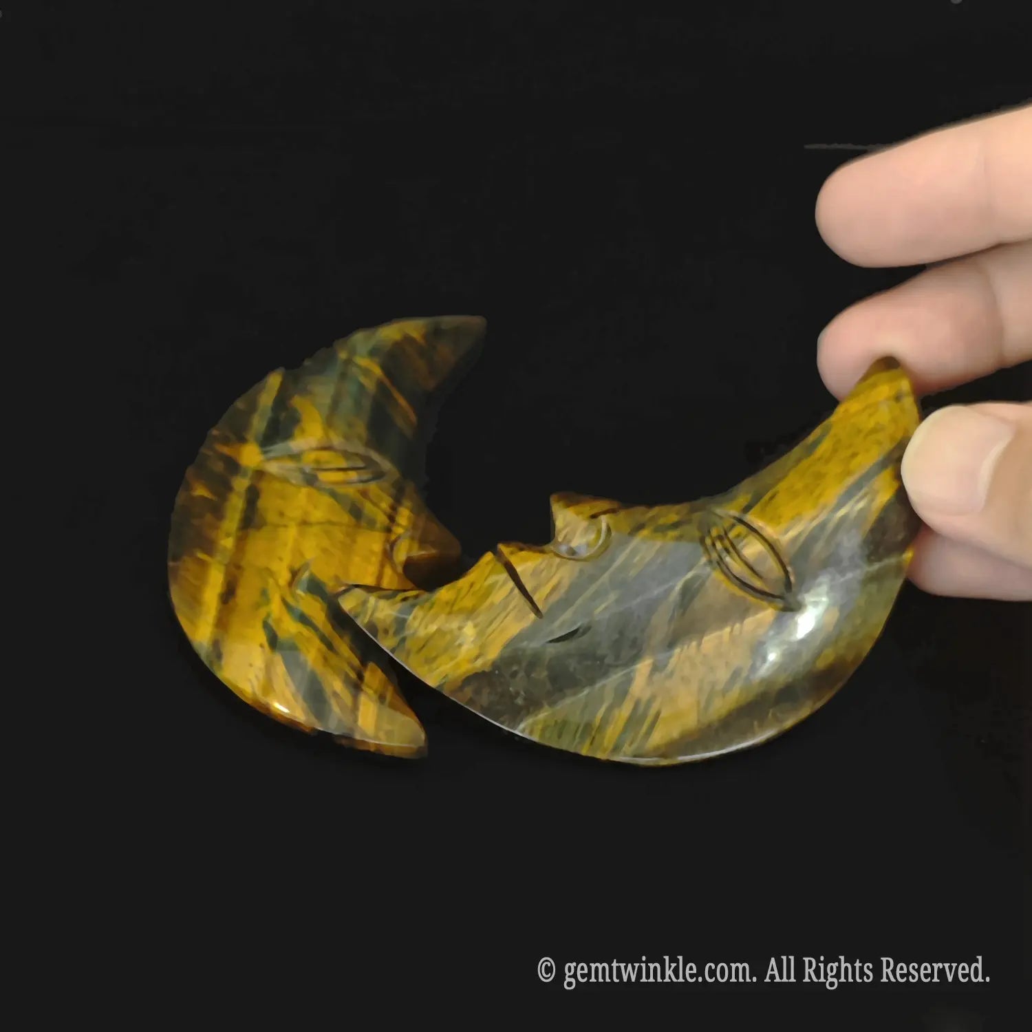 Profile view of a natural chatoyant crescent moon carving showing the detailed facial features