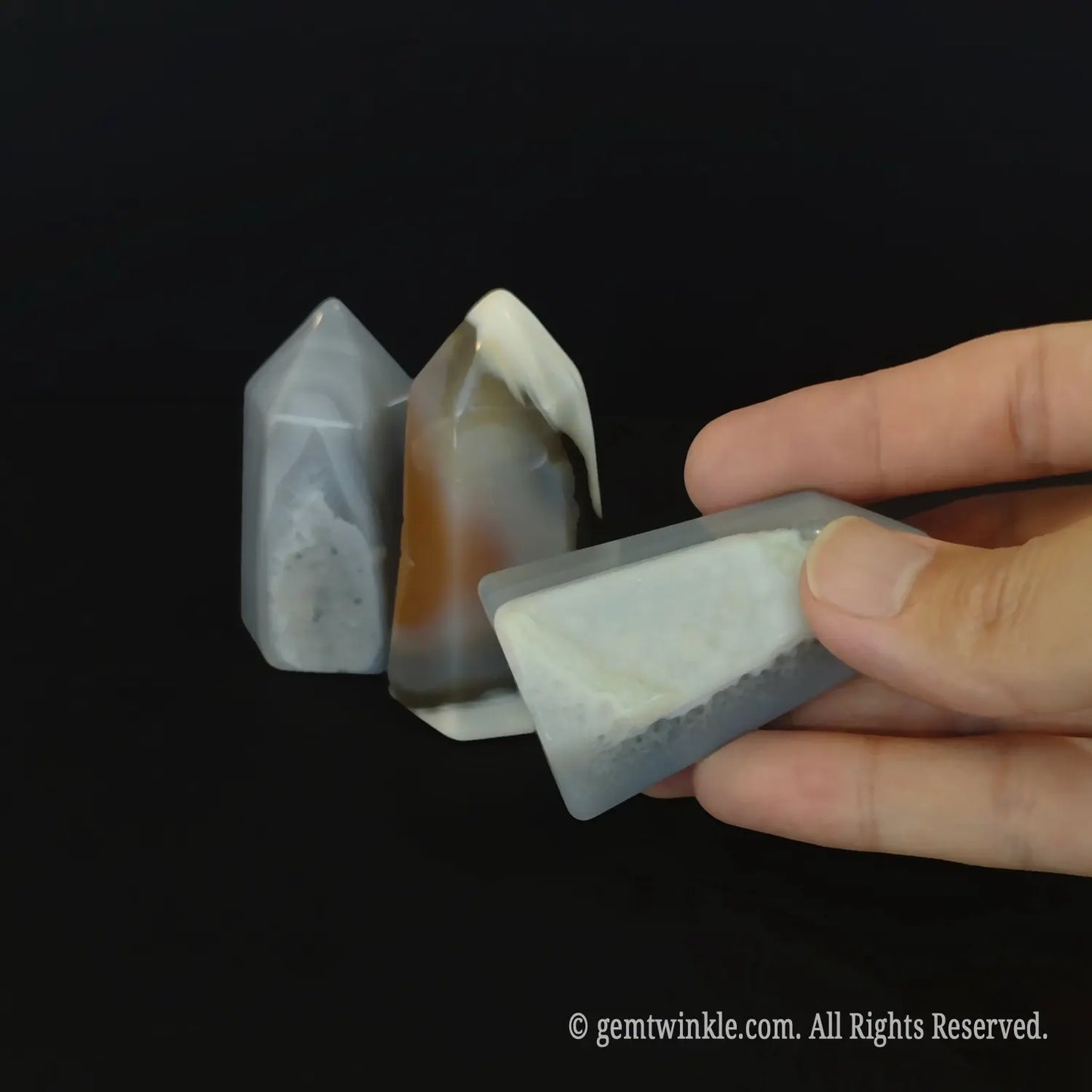 Side profile view of a 5cm natural geode obelisk showcasing polished geometric facets and rich mineral bands