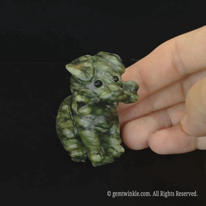 Detailed view of the green serpentine puppy statue highlighting organic mossy veins and contrasting white bone insert