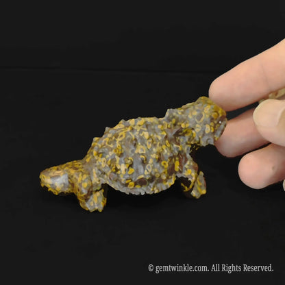 Handheld natural nuwa stone reptile carving featuring realistic lizard spikes and unique yellow green speckled textures