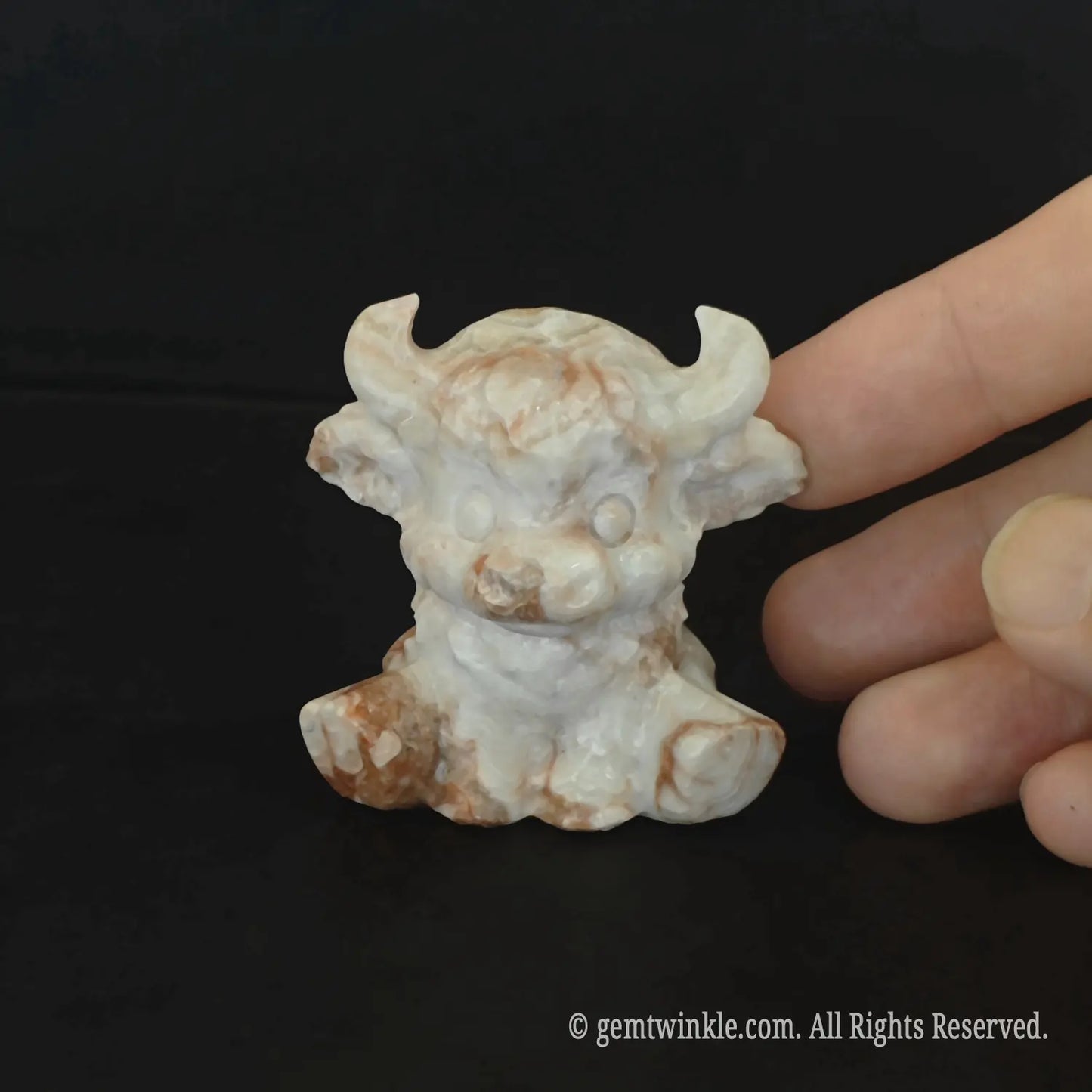 Frontal view of the 5cm red banded stone bull figurine displaying prominent ivory horns and cream parallel stripes