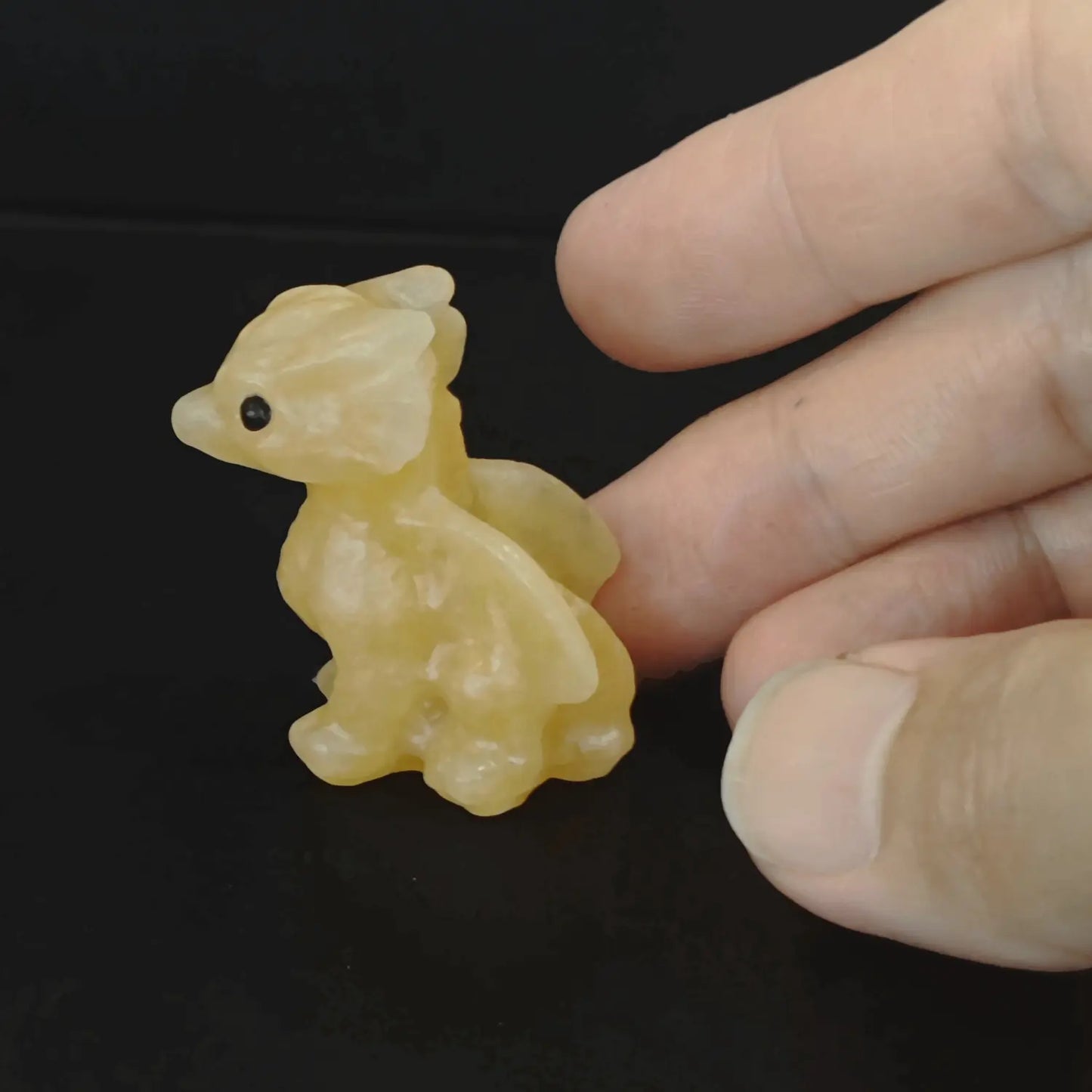 Angled side profile of a waxy yellow calcite baby dragon carving emphasizing the vibrant honey tone and spiky horn lines