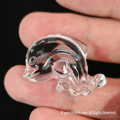 Back view of 30mm clear quartz dolphin held in hand highlighting light refraction and curved polish