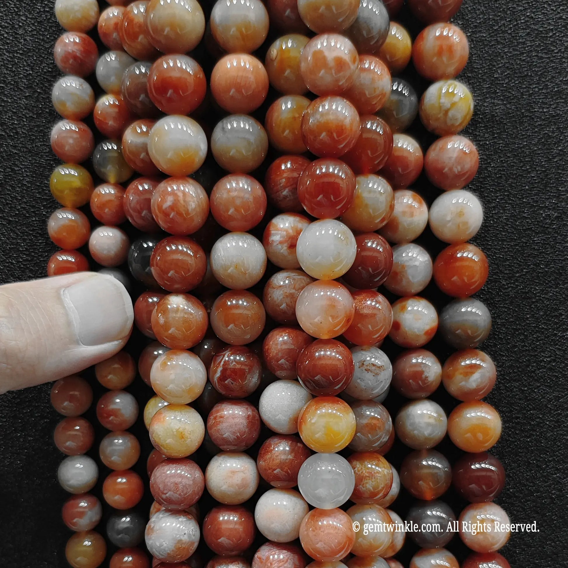 Hand holding multiple strands of genuine coral jade crystal beads to inspect patterns and quality