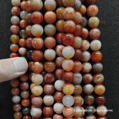Hand holding multiple strands of genuine coral jade crystal beads to inspect patterns and quality