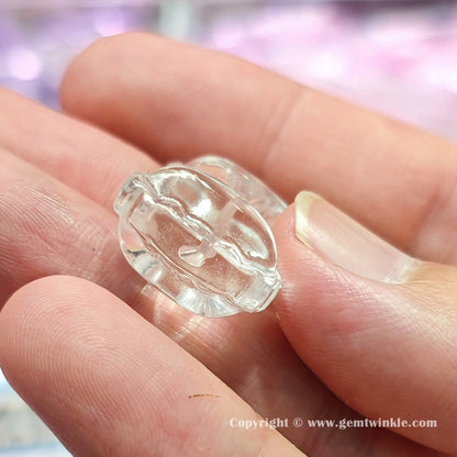 Handheld angle view of genuine rock crystal bow charm bead showcasing its clear carved profile on fingers