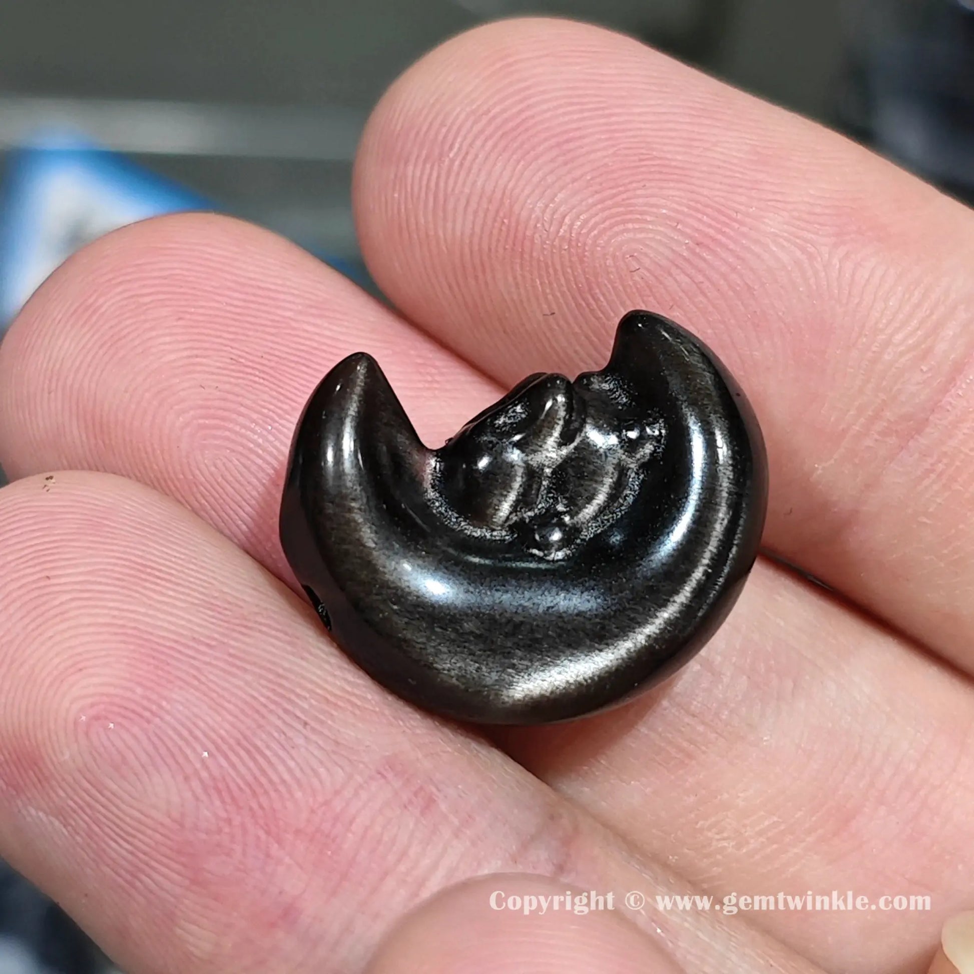 Close up details of genuine silver obsidian crescent moon rabbit focal charm showing bright metallic silver shimmer on hand
